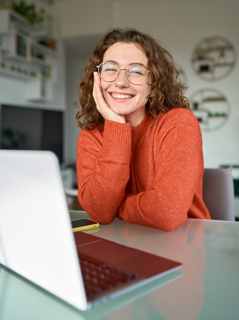 A woman smiling with a notebook on a desk